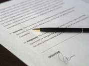 A black pen rests on a signed document with printed text and a visible signature line.